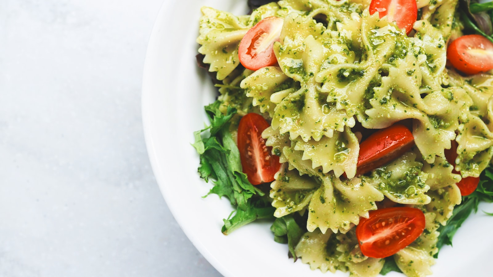A skillet of quick weeknight pasta tossed with greens on a wooden kitchen table.