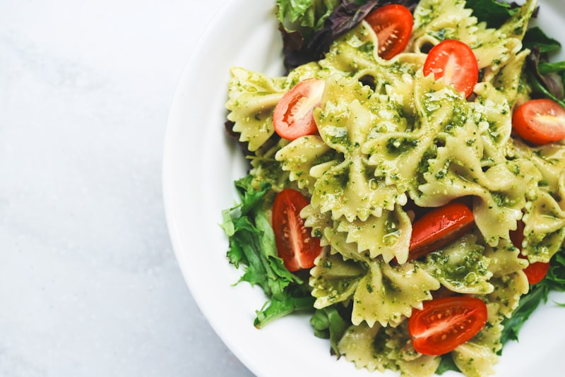 A skillet of quick weeknight pasta tossed with greens on a wooden kitchen table.