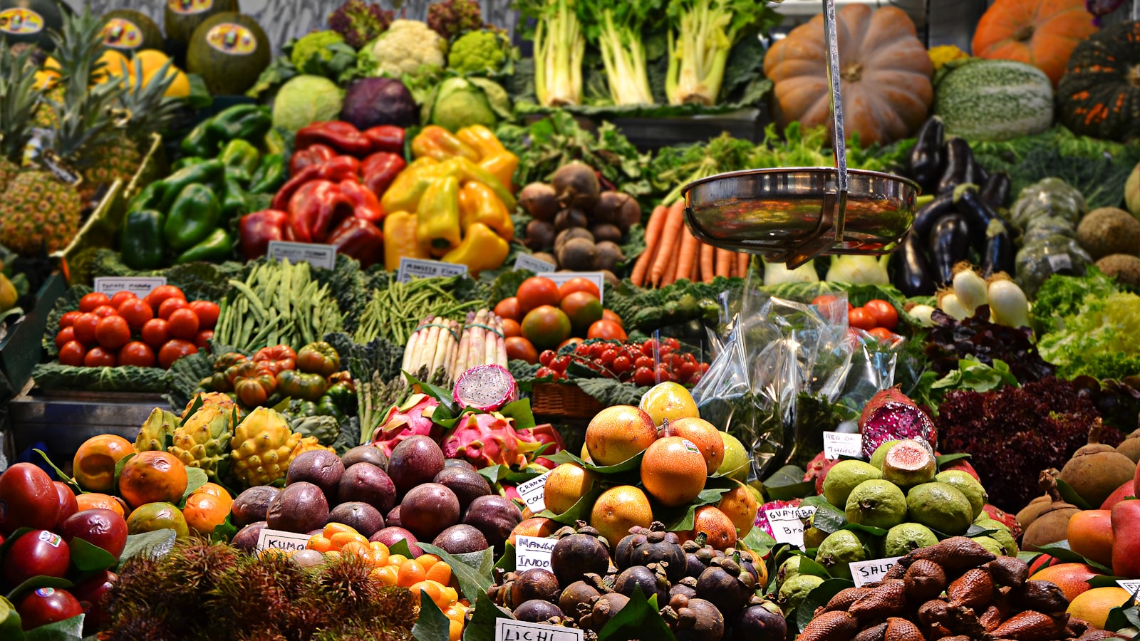 A market stall piled high with colorful fruits and vegetables in wooden crates.