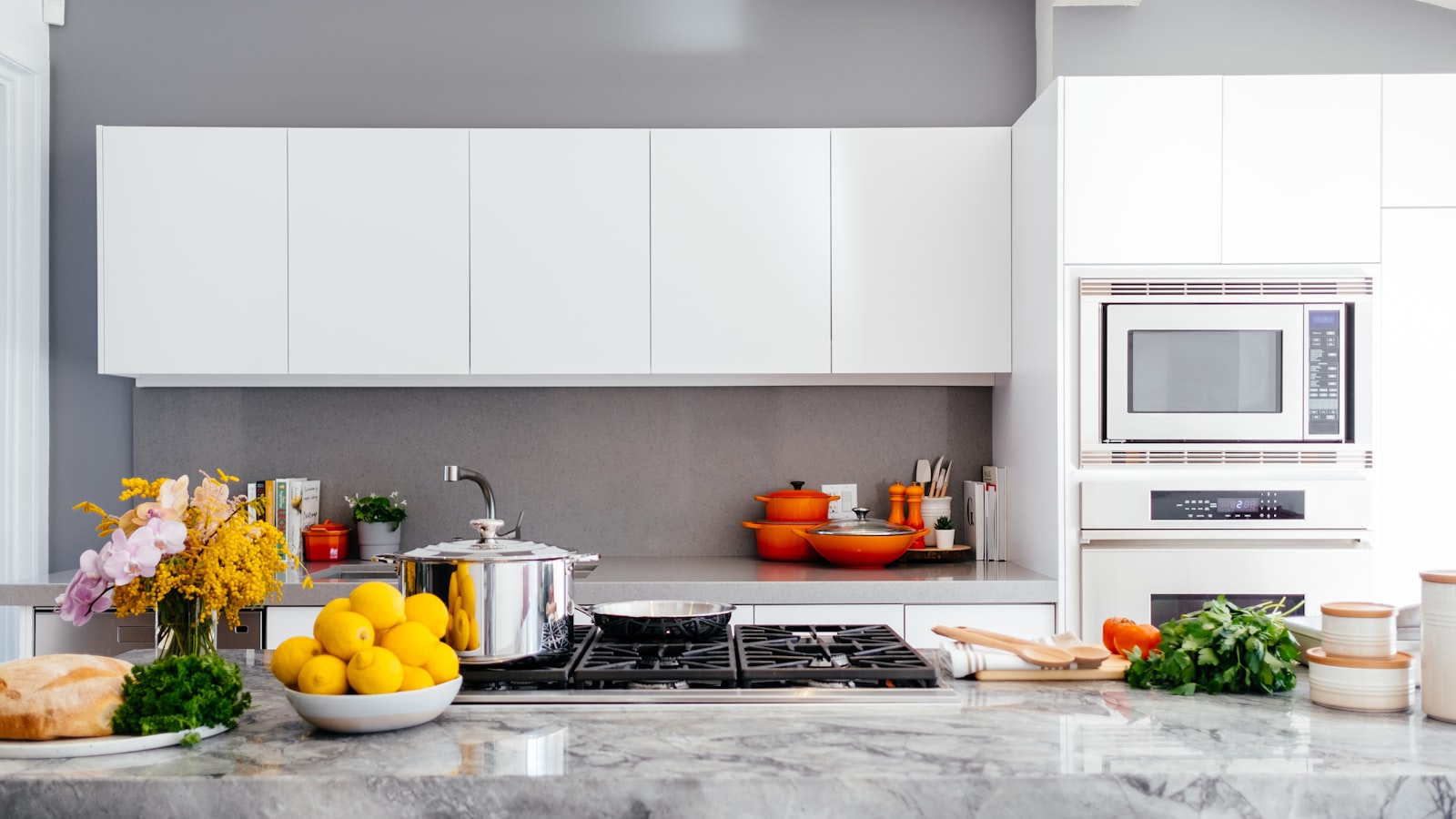 A compact, tidy kitchen with open shelving, hanging utensils, and a clear worktop.