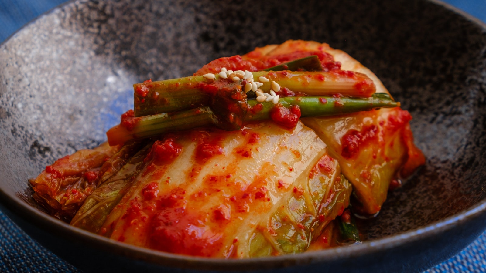 A glossy pan sauce being stirred with a wooden spoon in a stainless steel skillet.