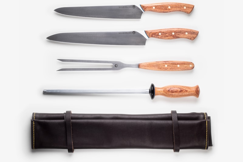 A chef's knife resting on a wooden cutting board beside freshly sliced vegetables.
