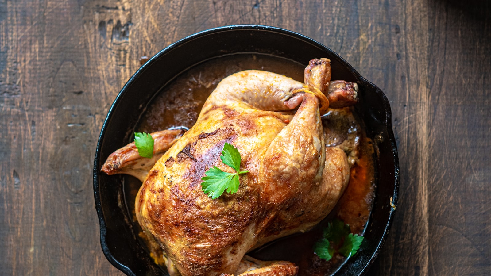 A golden-brown whole roast chicken resting on a wooden board.