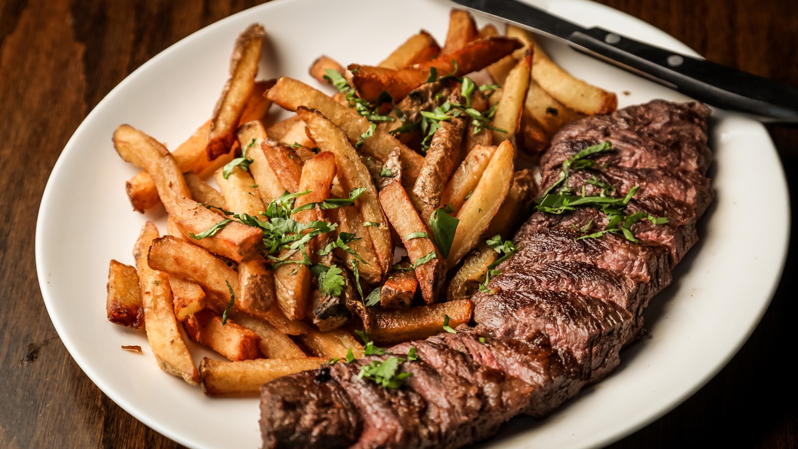 A thick steak searing in a hot pan with browned edges and rising steam.