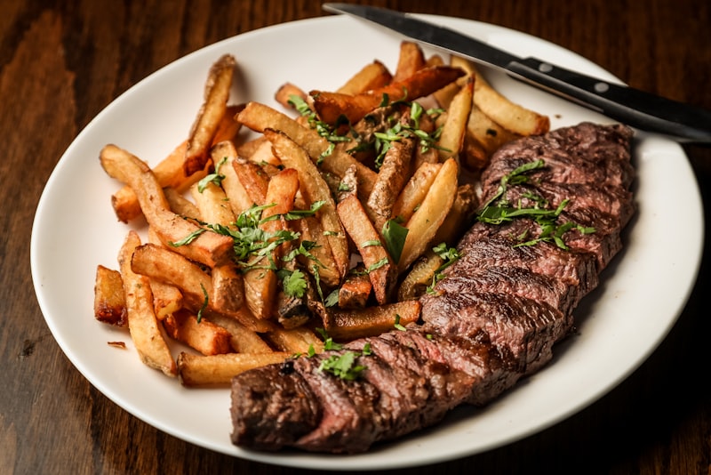 A thick steak searing in a hot pan with browned edges and rising steam.